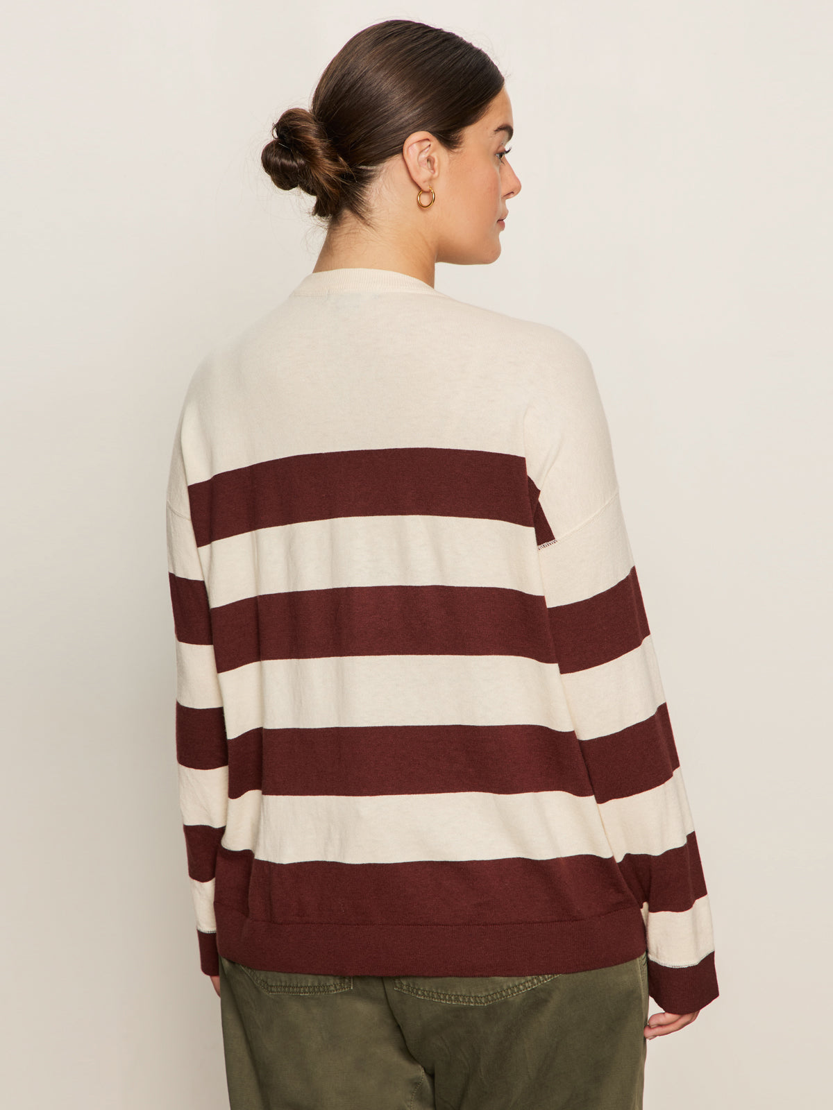 A person with dark hair in a low bun wears the Sanctuary Clothing 24 7 Popover Chicory Light Oat Extended Sizing sweater, shown from the back against a plain light background.