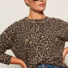 A woman in the Sanctuary Clothing 24 7 popover french kitty top and blue jeans poses confidently against a plain light background, wearing dark sunglasses.