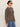 A woman in Sanctuary Clothing's 24/7 Popover French Kitty top and blue jeans, wearing sunglasses, stands against a plain light background facing sideways.