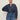 A woman with dark hair pulled back wears the Sanctuary Clothing personal best blouse moonshadow (extended sizing), a loose, long-sleeved denim top with metal buttons, paired with high-waisted blue jeans against a light background, one hand on her hip.