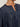 A close-up of a person wearing the Sanctuary Clothing personal best blouse moonshadow extended sizing—a dark blue denim top with a gathered yoke, shiny silver buttons, partially buttoned round neckline, and loose puffed sleeves. The face is not shown.