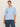 A woman stands against a beige background wearing the Sanctuary Clothing perfect sweater tee in blue powder (extended sizing) with blue jeans, her hair pulled back as she looks confidently at the camera.