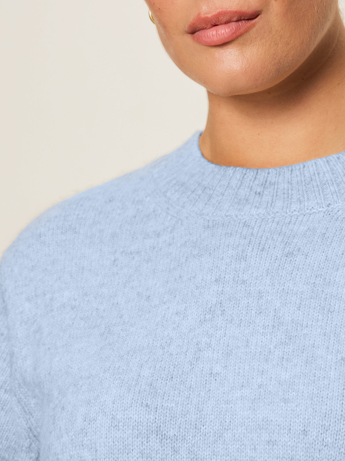 Close-up of a person wearing the Sanctuary Clothing perfect sweater tee in blue powder (extended sizing), showing only their lower face, neck, and upper shoulders against a neutral, blurred background.