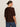A woman with brown hair in a low bun wears Sanctuary Clothing's perfect sweater tee chicory (extended sizing) and blue jeans, standing turned away against a plain light background.