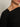 A close-up shows a person in the Sanctuary Clothing long sleeve shoulder twist top black extended sizing, featuring a knotted detail near the shoulder. The image highlights part of the neck, jawline, and lips against a neutral background.