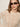 A woman with straight light brown hair wears oval dark sunglasses, gold hoop earrings, and the Sanctuary Clothing boheme popover light oat sweater, standing against a light background.