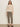 A woman with long straight hair and a neutral expression stands against a plain wall, wearing Sanctuary Clothing's cadence 90 straight crop jeans in french kitty print, paired with a cream knit sweater and black slip-on shoes.
