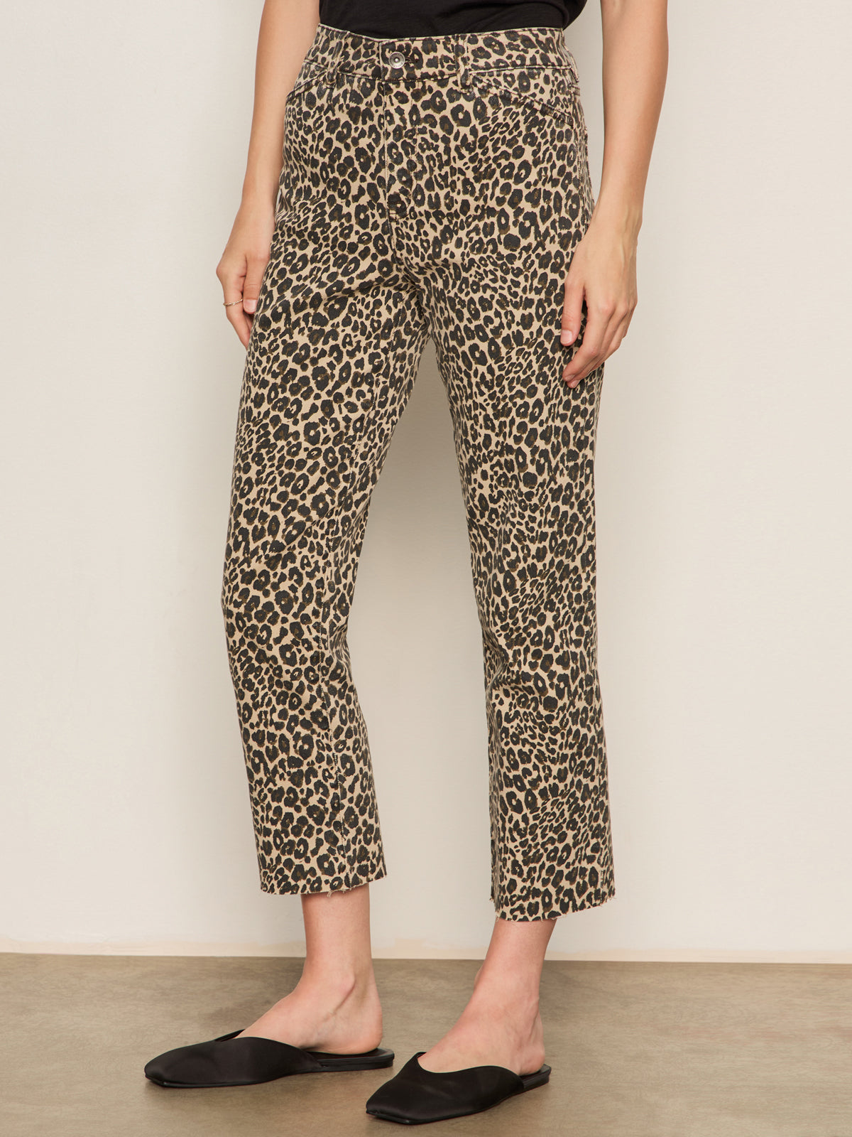 A person wearing Sanctuary Clothing's cadence 90 straight crop jeans in the French Kitty leopard print, paired with black slip-on flat shoes and standing against a neutral background.