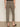 A person stands facing away in Sanctuary Clothing’s cadence 90 straight crop jeans in the French Kitty leopard print, paired with a black top and black slip-on shoes against a plain, neutral background.