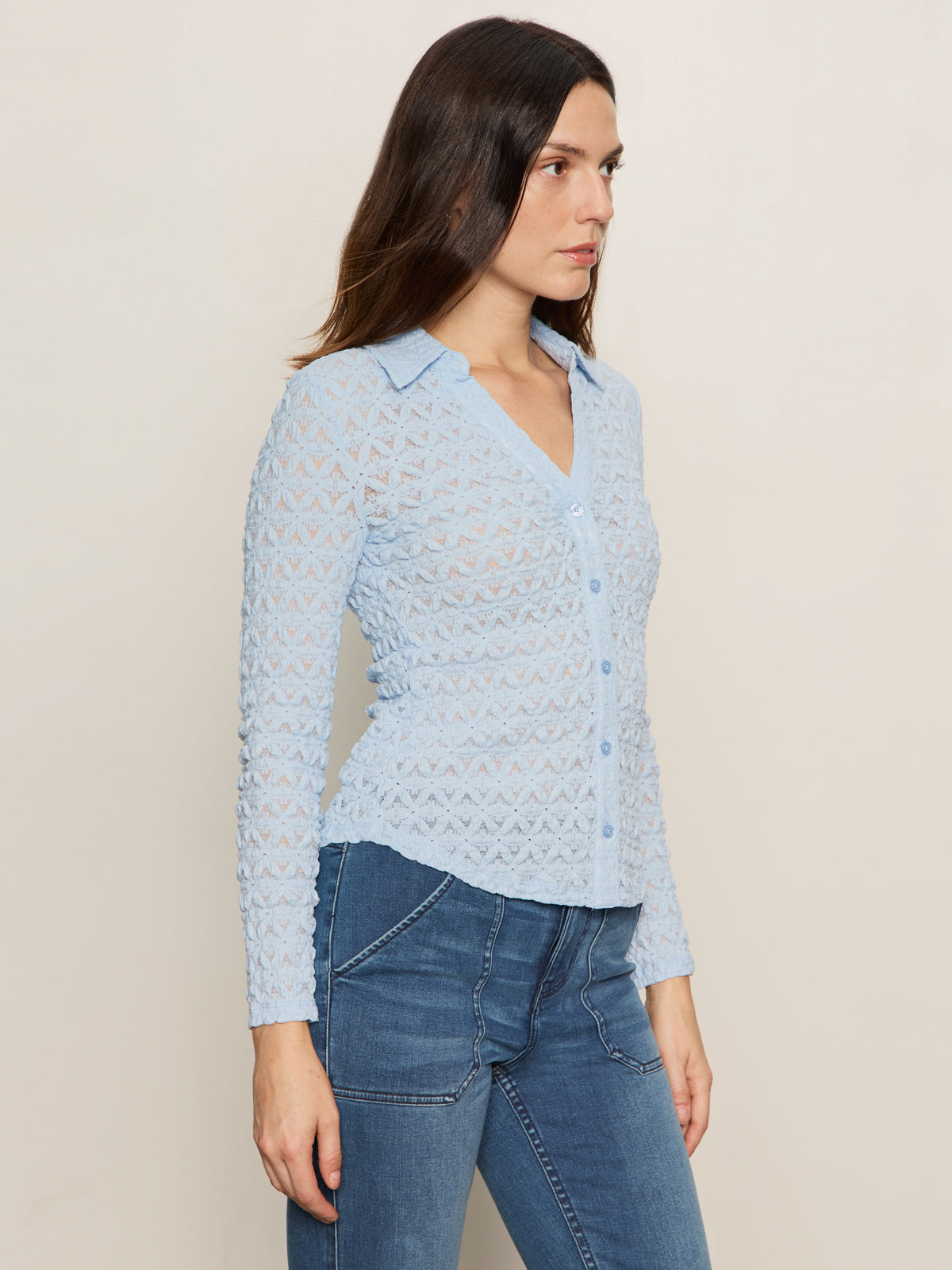 A woman stands sideways wearing the Sanctuary Clothing Dreamgirl Lace Button Up Top in blue powder with blue jeans, set against a plain, neutral background.