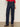 A person models the lower half, wearing Sanctuary Clothing’s soleil 90s straight jeans in indigo dark raw rinse, paired with a red textured top and leopard-print flats against a plain light background.