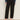 A person models the Sanctuary Clothing ponte barrel trouser in black, paired with a blue long-sleeve shirt and black heeled mules, standing against a plain light background. The waist-up photo excludes the person's face.