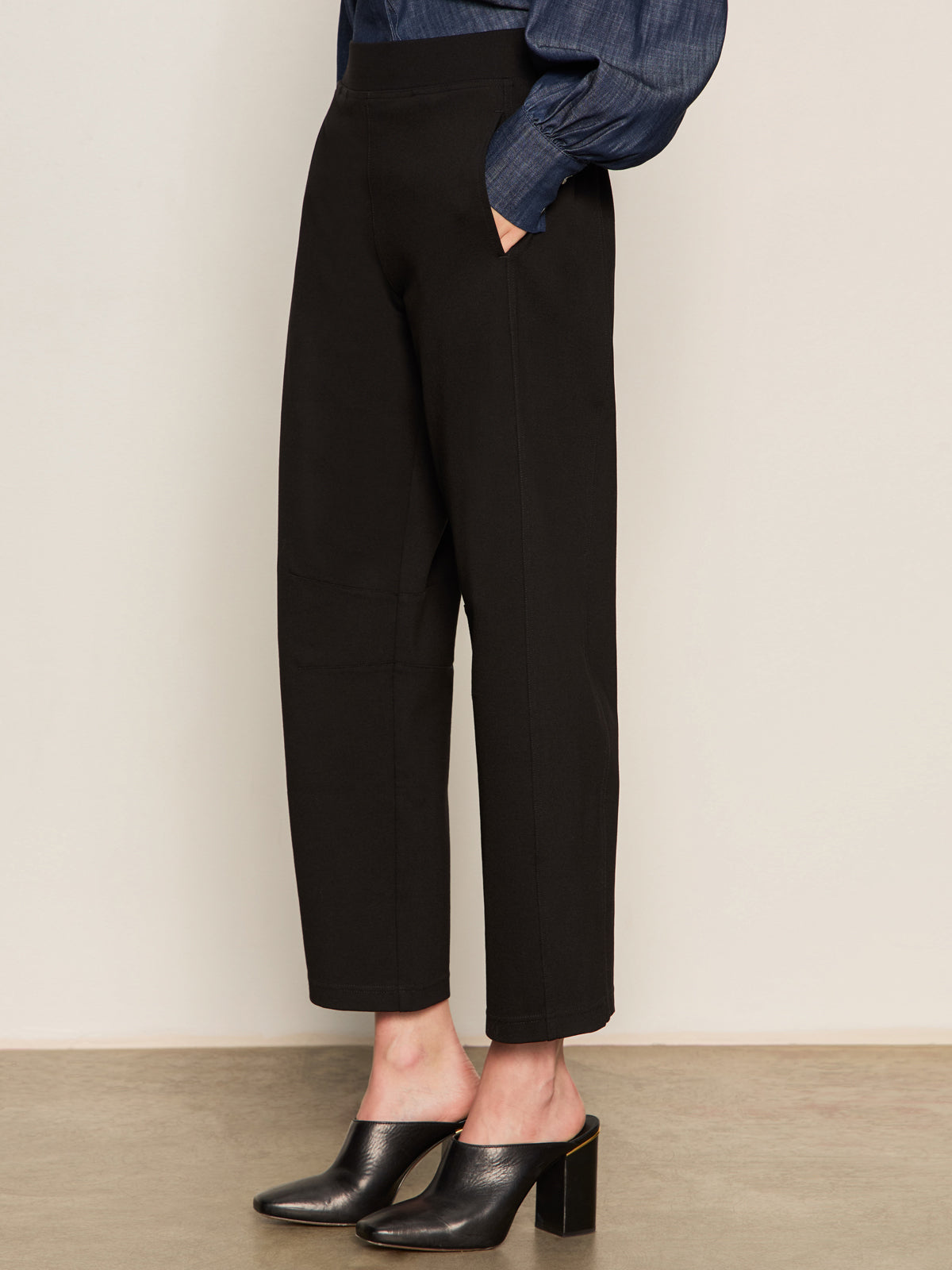 Model wears the Sanctuary Clothing ponte barrel trouser in black, paired with heeled mules. Image is cropped from the waist down, showing hands in pockets while standing on a plain floor.