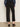 A person wearing Sanctuary Clothing's ponte barrel trouser in black, shown from the back indoors against a neutral background, styled with a dark blue long-sleeve blouse and black heeled mules.