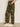Person wearing Sanctuary Clothing boyfriend utility pant rambler camo, paired with white sneakers. Only the lower half of the body is visible, standing on a light floor against a plain beige wall.