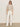 A person stands against a plain background wearing sunglasses, the Sanctuary Clothing perfect sweater tee in heather pearl, white high-waisted wide-leg pants, and white sneakers.