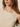 A woman with long, light brown hair models the Sanctuary Clothing asymm shoulder twist top in heather pearl; this sleeveless knit features an asymmetric neckline with a twisted detail on one shoulder. Only her upper torso and part of her face are visible.