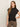 A woman with long, light brown hair wears the Sanctuary Clothing draped sleeveless mock neck top in black and leopard print pants, standing against a plain light background with one hand on her hip.