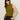 A woman with straight brown hair wears the "fuzzy shell martini olive" sleeveless turtleneck sweater by Sanctuary Clothing, paired with black sunglasses and pants, standing against a plain light background with hands in her pockets.