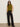 A woman stands against a light wall with her hands in her pockets, wearing dark sunglasses and Sanctuary Clothing’s modern gab trouser in black, paired with a sleeveless olive green turtleneck top.