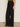A person wearing Sanctuary Clothing's modern gab trouser in black and black flats stands against a light wall, with only the lower half of their body visible and their arm by their side.