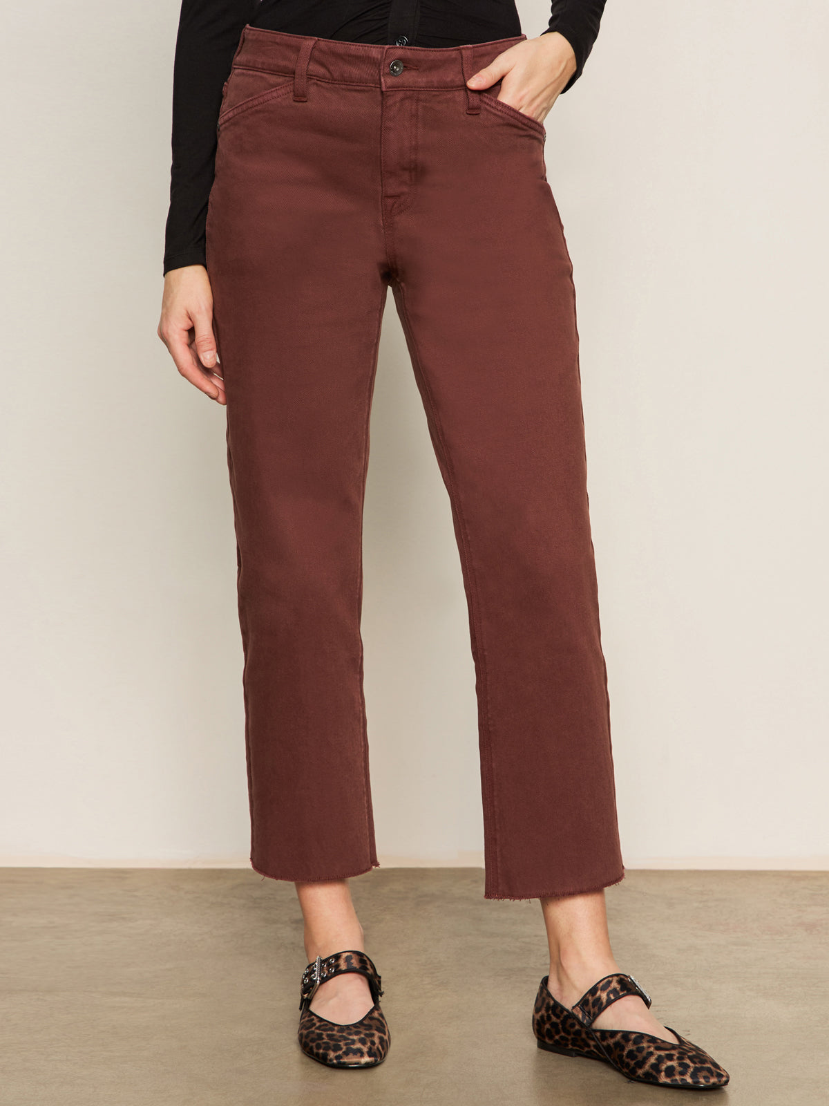 A person, visible from the waist down, stands against a light wall wearing Sanctuary Clothing's cadence 90s straight crop jeans in chicory and leopard print Mary Jane shoes.