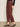A person wears Sanctuary Clothing's cadence 90s straight crop jeans in chicory, paired with a black long-sleeve top and leopard-print Mary Jane flats, standing against a neutral background.