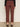 A person wears Sanctuary Clothing’s cadence 90s straight crop jeans in chicory, featuring a cropped, straight-leg maroon style with raw hems and back pockets. They pair it with a black long-sleeve top and leopard-print flats.
