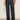 A person wears Sanctuary Clothing’s ekara slim wide jean in indigo dark rinse wash, featuring prominent seams and front buttons, paired with an animal print long-sleeve blouse and black shoes against a plain background.