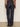 A person stands facing away, wearing Sanctuary Clothing's ekara slim wide jean in indigo dark rinse wash, paired with a brown leopard print long-sleeve blouse; black heeled shoes are partially visible.
