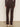 A person faces away wearing Sanctuary Clothing's corduroy Hayden bootcut pant in semi sweet, paired with a dark long-sleeve top and beige shoes. They stand on a light floor against a plain light wall.