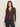 A woman with long brown hair wears the textured knit dreamgirl top semi sweet by Sanctuary Clothing—a dark brown, collared button-up cardigan with long sleeves—paired with dark blue jeans, standing against a plain light background and looking at the camera.