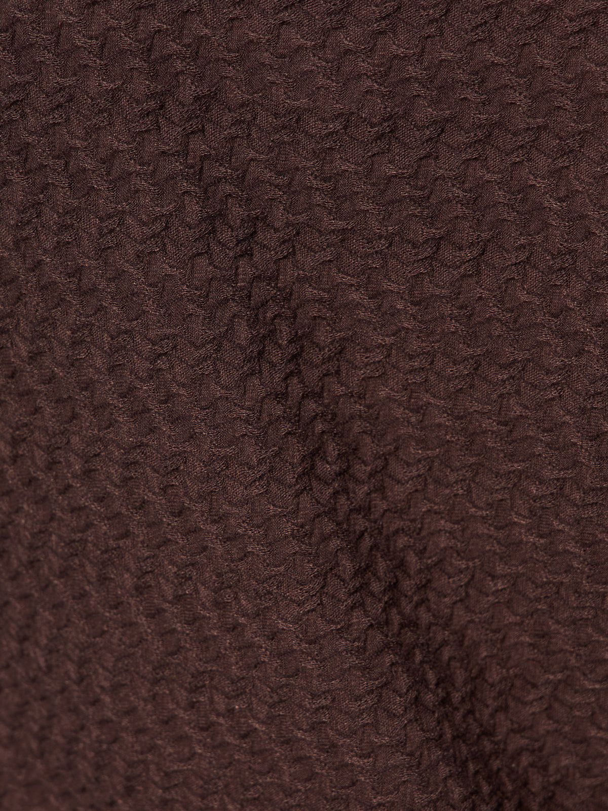 Close-up of the Sanctuary Clothing textured knit Dreamgirl Top in semi-sweet, featuring a brown fabric with a subtle, repeating zigzag pattern and gentle folds.
