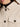 Close-up of a person wearing Sanctuary Clothing’s “the corduroy shacket mother of pearl”—a light beige jacket with black buttons and front pocket—over a black turtleneck, showing only the lower half of the face and upper torso.