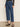 Wearing Sanctuary Clothing's the marine jeans aspen—high-waisted, cropped blue jeans with front patch pockets—a person pairs them with a black long-sleeve top and leopard print Mary Jane flats against a plain background.