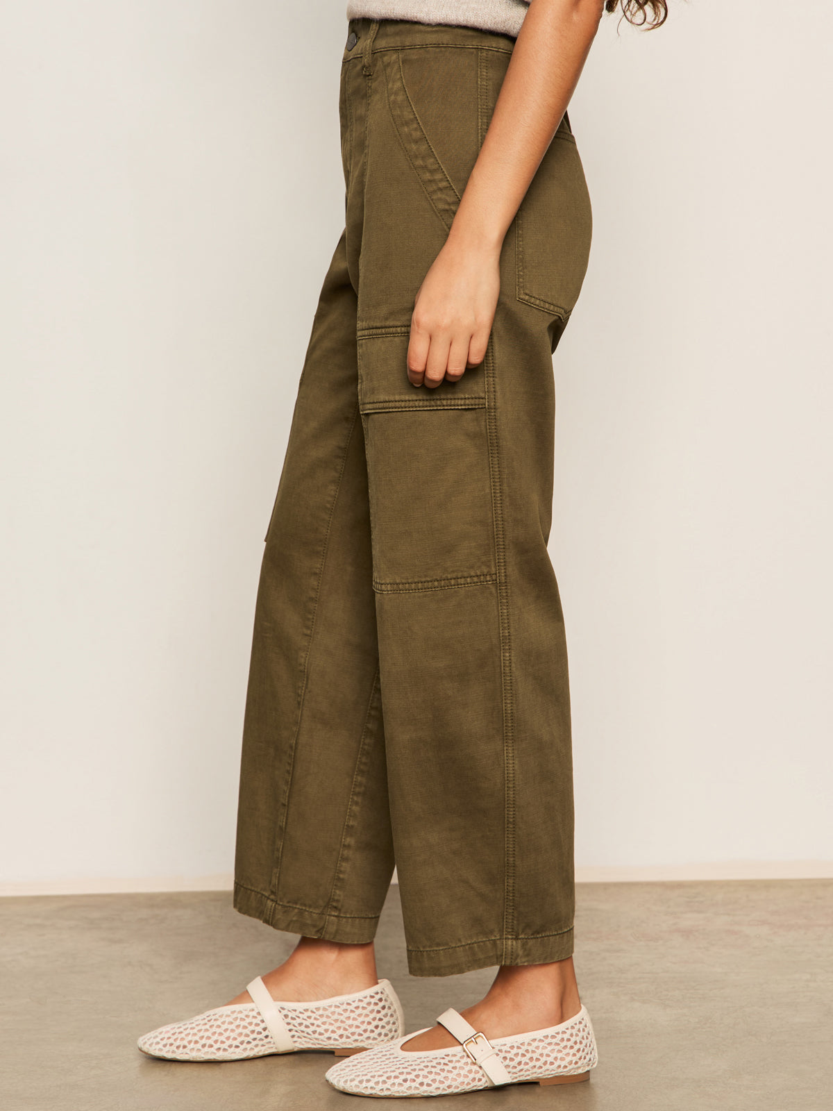 A person stands indoors wearing the Sanctuary Clothing boyfriend utility pant in kalamata. Only their lower body is visible, with wide-leg cargo pants against a plain background.