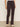 A person wears Sanctuary Clothing's corduroy hayden bootcut pant semi sweet petites in dark brown with front patch pockets, paired with a white top and light beige shoes, standing against a plain background.
