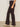 A person in Sanctuary Clothing's corduroy hayden bootcut pant semi sweet petites and light beige heeled boots stands sideways against a plain light-colored wall.