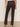 A person stands facing away, wearing Sanctuary Clothing's corduroy hayden bootcut pant semi sweet petites, paired with a white top and beige heeled shoes on a light floor against a plain background.