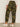 A person faces away, wearing Sanctuary Clothing’s boyfriend utility pant rambler camo (extended sizing)—high-waisted green camo pants with patch pockets and a relaxed fit—paired with white sneakers against a neutral background.