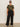 A woman stands against a plain wall wearing sunglasses, a camouflage tee, white sneakers, and Sanctuary Clothing's runway ponte trouser in black (extended sizing). Her hair is pulled back with a neutral expression.