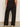 A person faces away from the camera, wearing Sanctuary Clothing's runway ponte trouser black extended sizing and white sneakers with black details, set against a neutral indoor background.