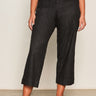 Someone wearing the Marine Jeans After Hours (extended sizing) by Sanctuary Clothing, featuring black cropped wide-leg style with front patch pockets, and black pointed-toe flats, stands against a light wall and concrete floor.