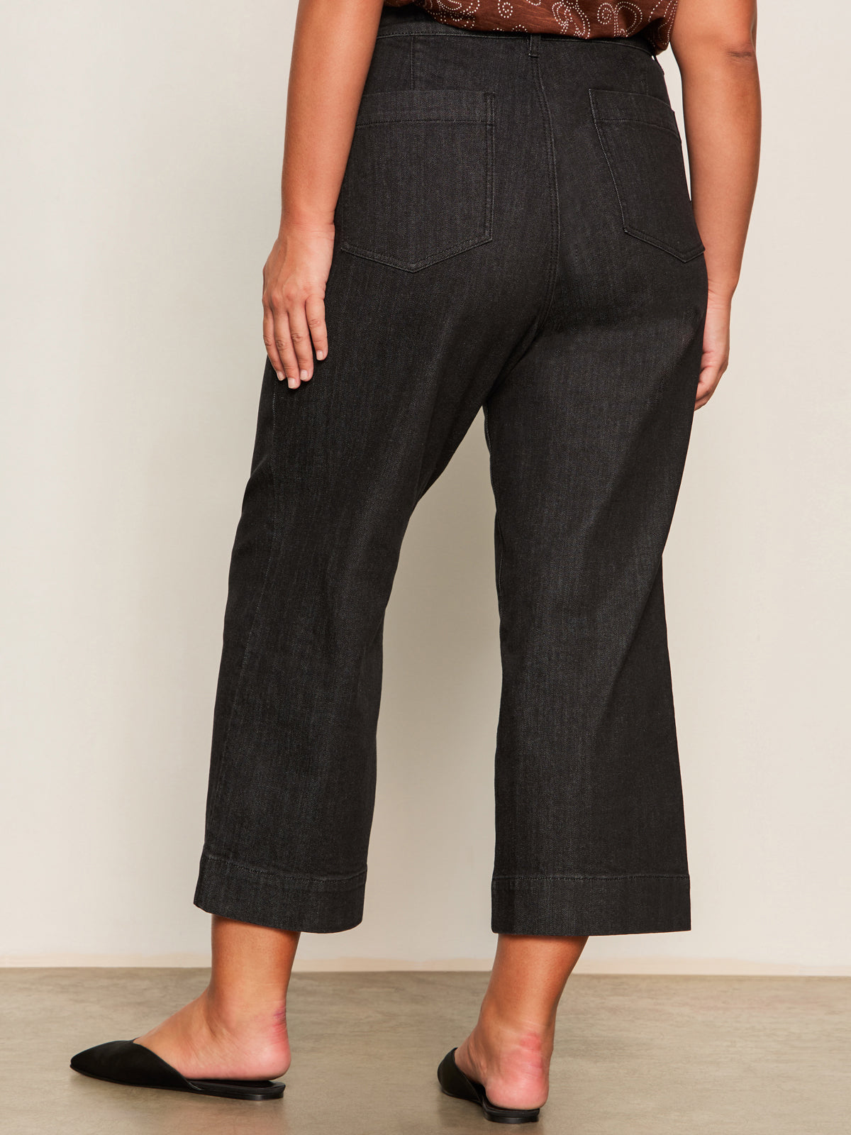 A person is indoors with their back to the camera, showing only their lower half, wearing Sanctuary Clothing's the marine jeans after hours extended sizing.