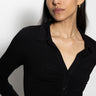 A person with long dark hair wears the "dreamgirl button up black" by Sanctuary Clothing, paired with gold jewelry, and looks to the side against a plain white background.