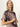 A woman with long blonde hair wears the Sanctuary Clothing sanc souvenir shirt mesa palm—a short-sleeved top with a bold geometric palm pattern—standing against a plain light background and looking slightly upward with a neutral expression.