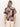 A person with long, straight blonde hair is seen from the back wearing the Sanctuary Clothing sanc souvenir shirt mesa palm—a short-sleeve dark shirt with a large light leaf pattern—paired with light beige pants against a plain background.