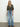 A woman with long blonde hair poses in the Sanctuary Clothing wild love tie top french kitty, styled with light blue wide-leg jeans and black shoes against a plain background.