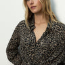A woman with long blonde hair wears the Sanctuary Clothing wild love tie top french kitty, styled with light blue jeans against a plain white background.