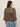 A woman with long brown hair wears gold hoop earrings, light blue jeans, and Sanctuary Clothing's the adore blouse french kitty—a sheer, high-neck leopard print top with a keyhole back—standing against a plain light background.
